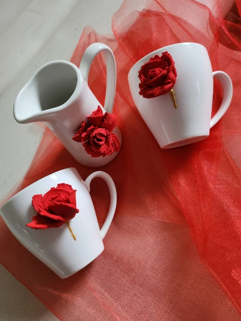 Tazze e piccolo bricco in ceramica bianca decorati a mano con rose rosse in pasta scultura